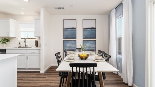 Image of an open concept dining room with a table, chairs, large windows and art on the wall.