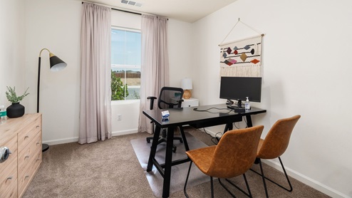 A home office with a large window, desk and chairs