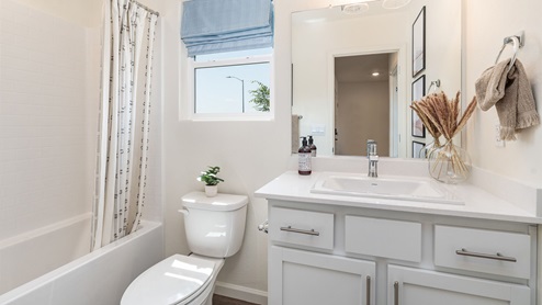 Bathroom with white cabinets, white countertops, a shower and toilet