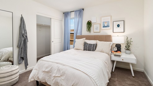 Guest bedrooms with a full bed, end table, and a large window
