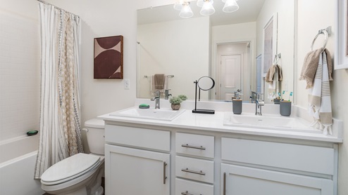 Bathroom with white cabinets, white counter tops, a shower and toilet
