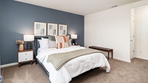 Primary bedroom with large windows, matching end tables, and art on the wall