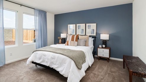Primary bedroom with large windows, matching end tables, and art on the wall
