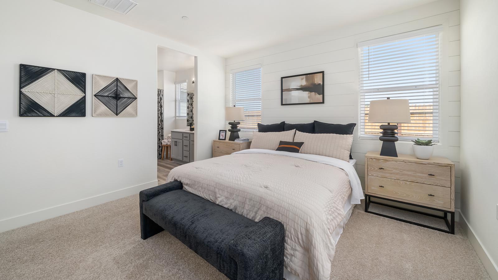 Interior photo of primary bedroom with king size bed, matching end tables and large windows