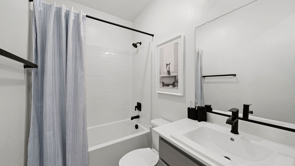 bathroom with blue shower curtain and grey cabinets.