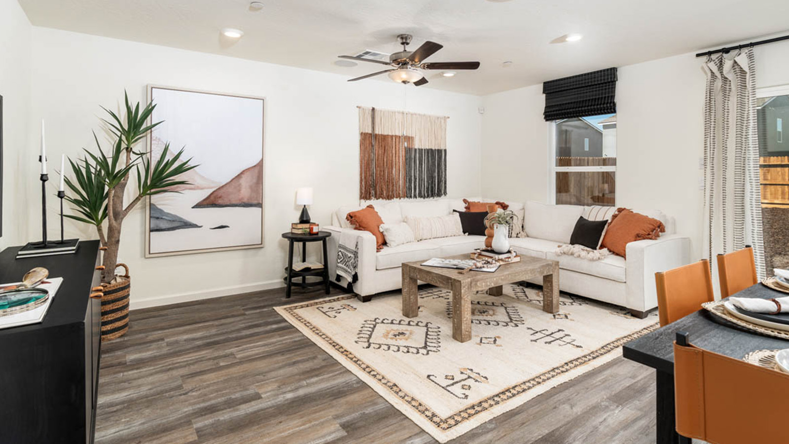 Living room with a white sectional couch that has orange accents.