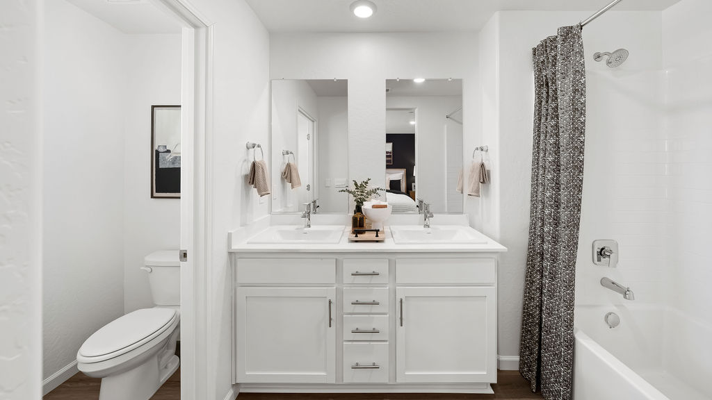 Bathroom with white cabinets and grey shower curtain.