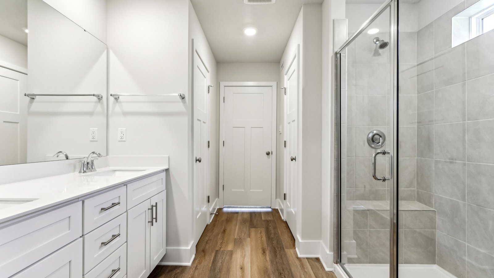 Primary ensuite bathroom with double bowl vanity and walk in shower with glass door