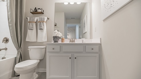 Secondary bathroom with white cabinets and countertops
