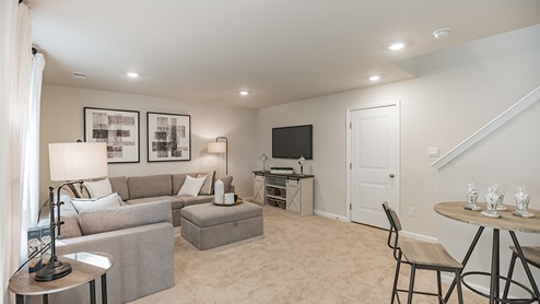 finshed basement rec room with light brown carpet and direct access to 2 car garage