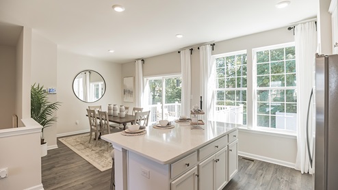 Open kitchen overlooking the dining area with island and white cabinets and countertops