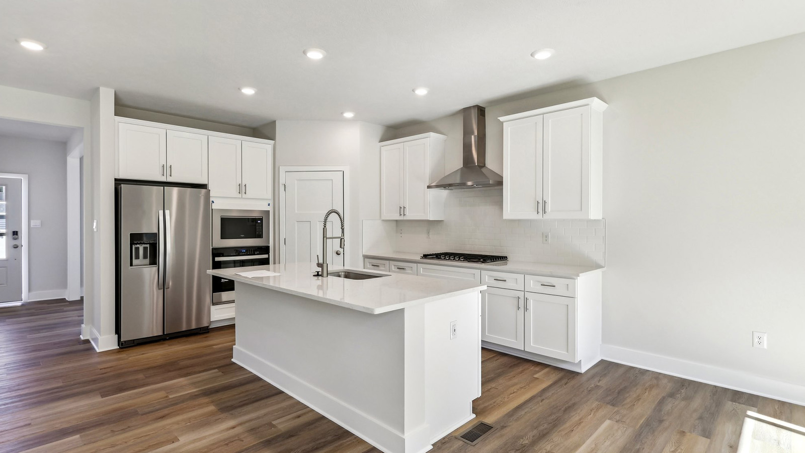 Large gourmet kitchen with stainless steel appliances and range hood