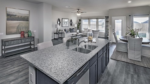 large kitchen island with sink overlooking living area with large windows