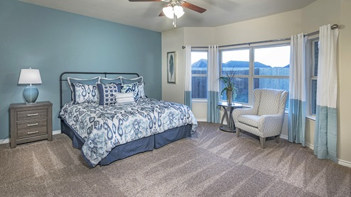 large primary bedroom with blue accent wall and furniture with large windows
