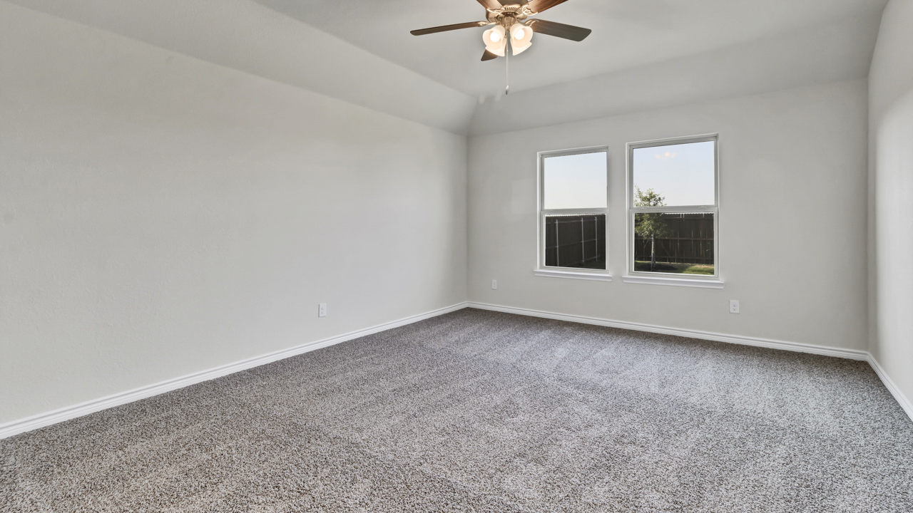 large primary bedroom with carpet, windows and a ceiling fan