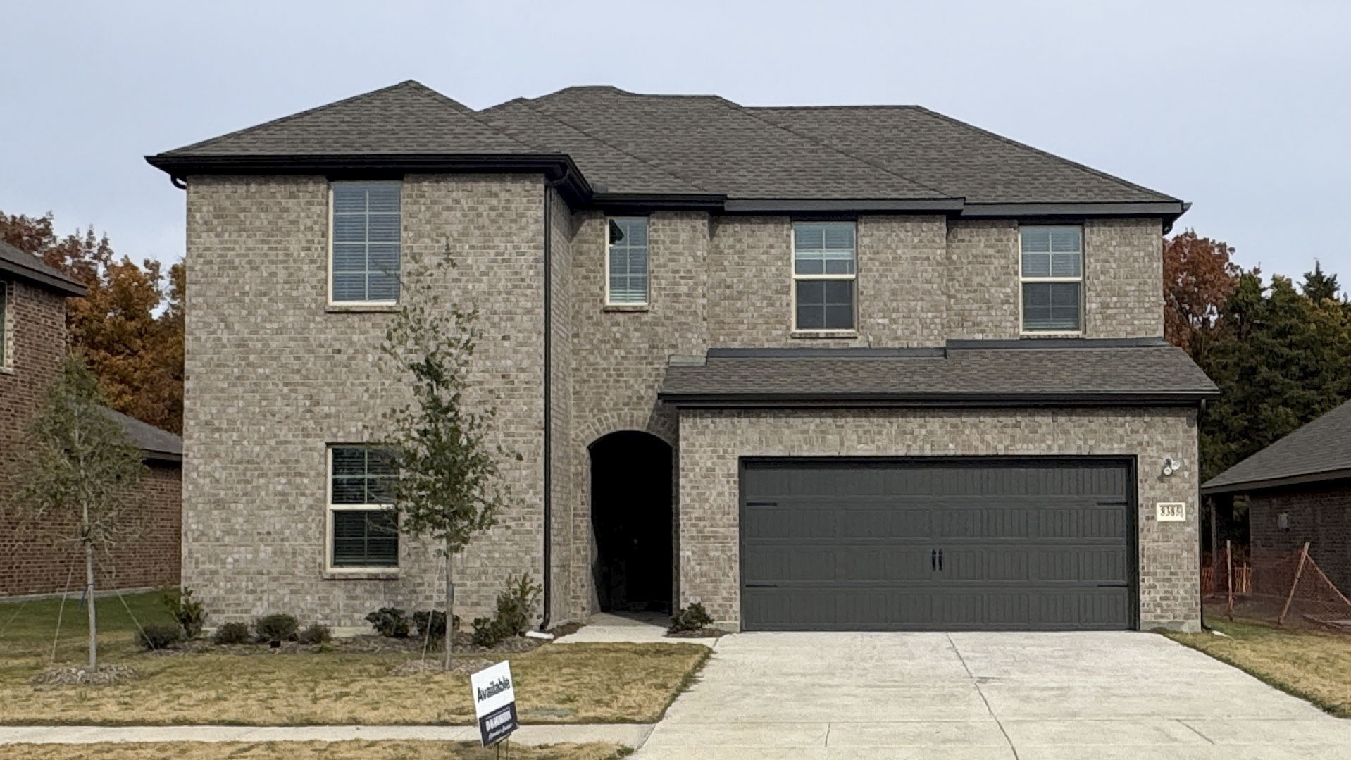 two story home with light colored brick exterior with large windows facing the front yard