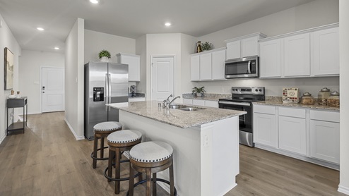 1304 Quest Bridge Road Model kitchen area with granite counters and white cabinets with view of interior entry