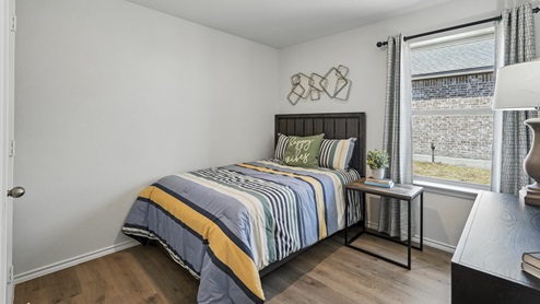 bedroom featuring a twin bed with orange and blue bedding, a dresser and a window