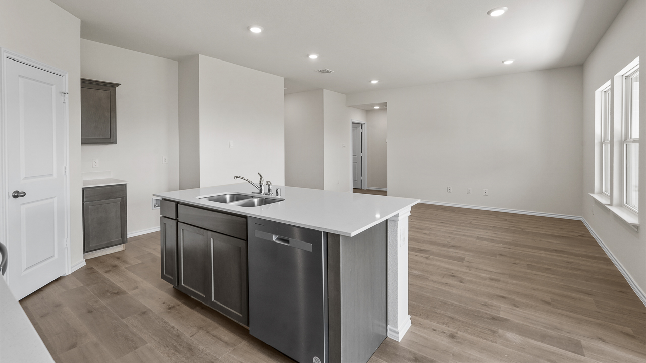 open concept living room with view from kitchen showing island with whtie counter and brown cabinets