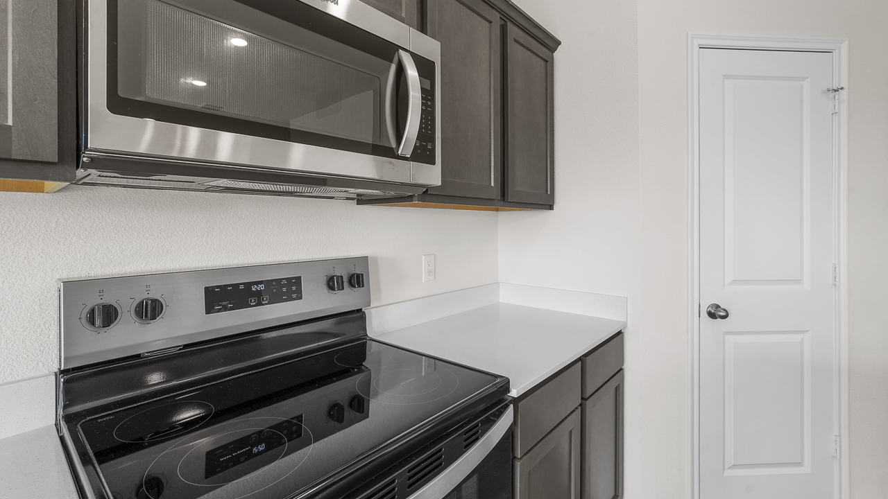 close up of brown cabinets and stainless steel microwave and oven
