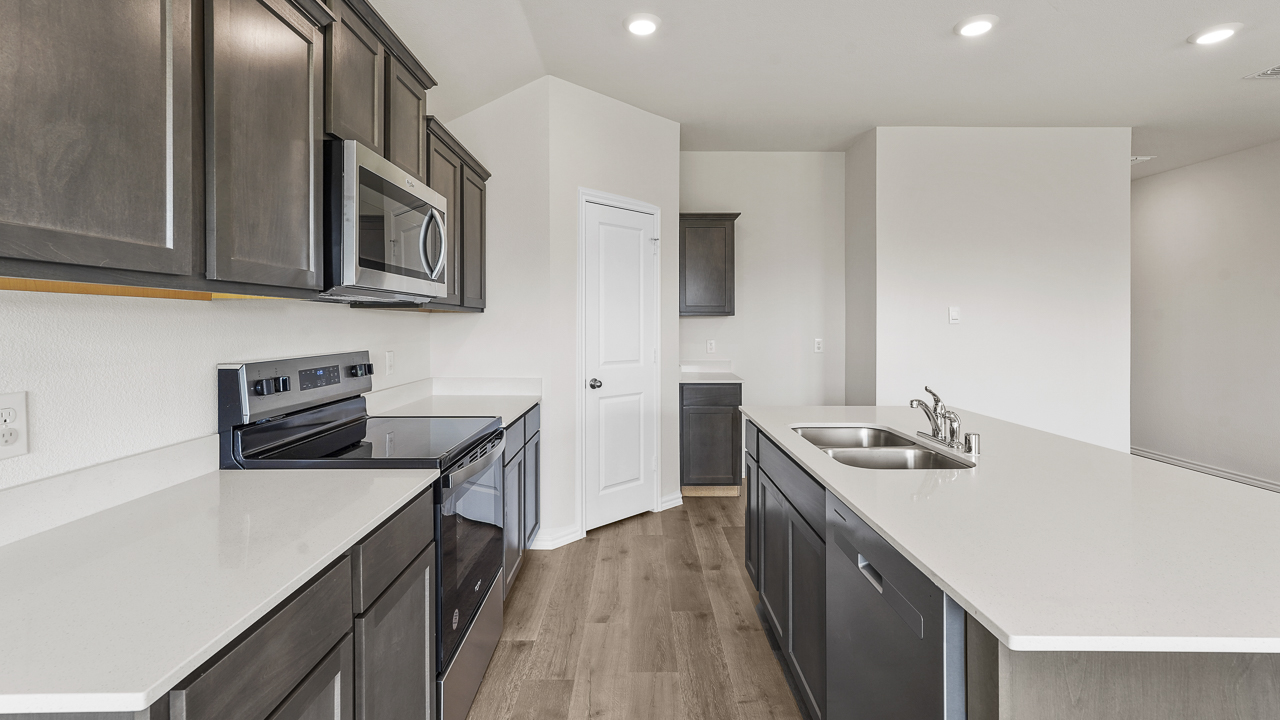 view into kitchen with elongated white countertops and brown cabinets