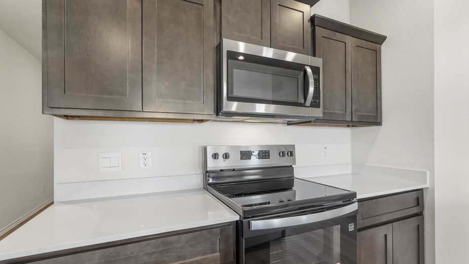 close up of brown cabinets and stainless steel microwave and stove