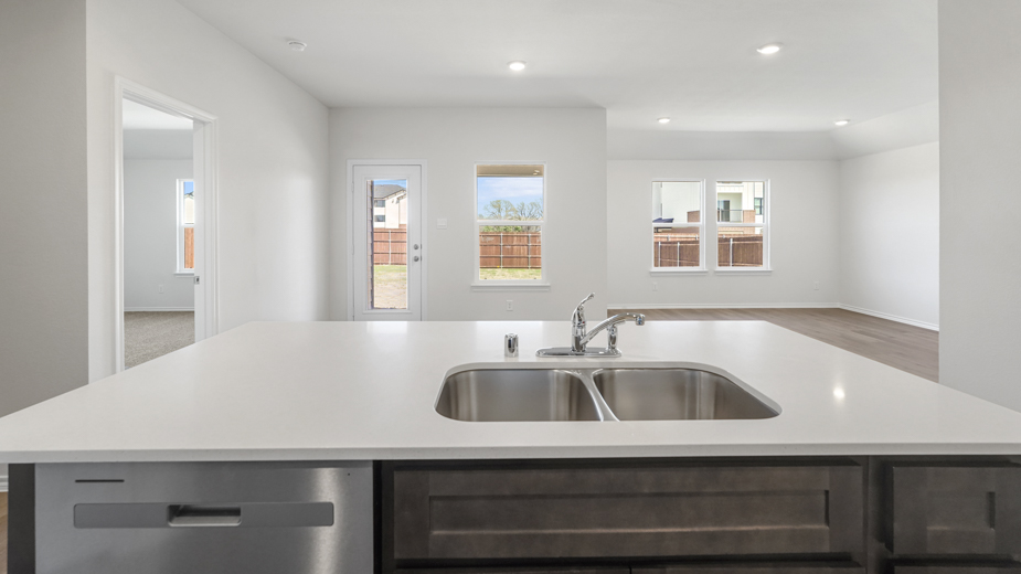 close up of large island with white counters overlooking living room and back door