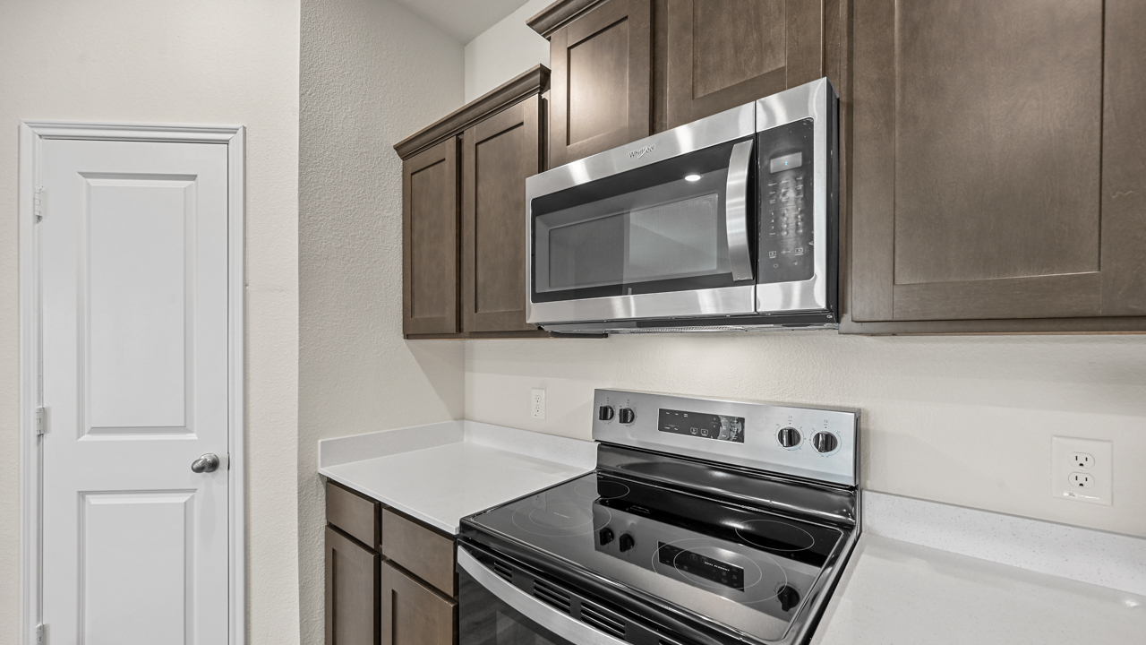 close up of brown cabinets and stainless steel microwave and oven