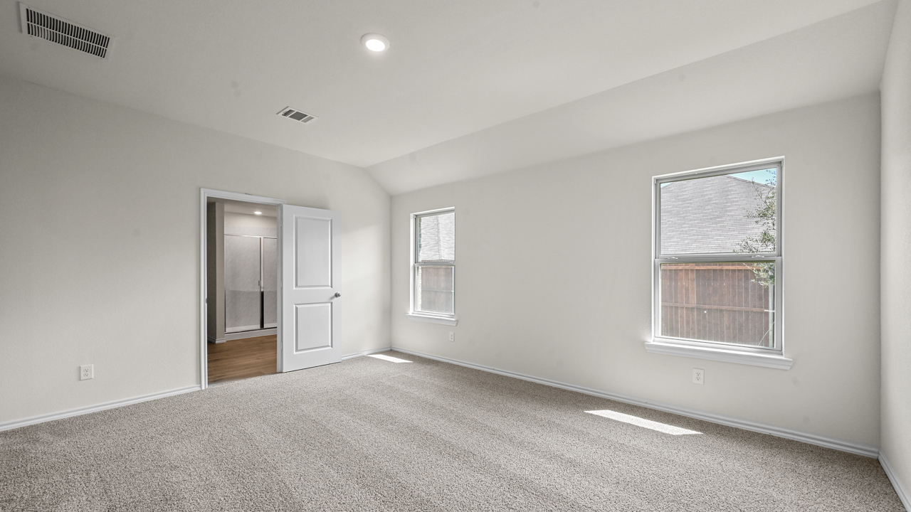 primary bedroom with two windows and bathroom door