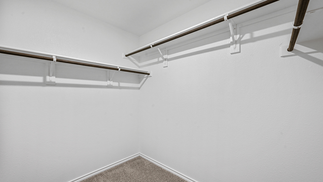 large walk in closet with hanging rods