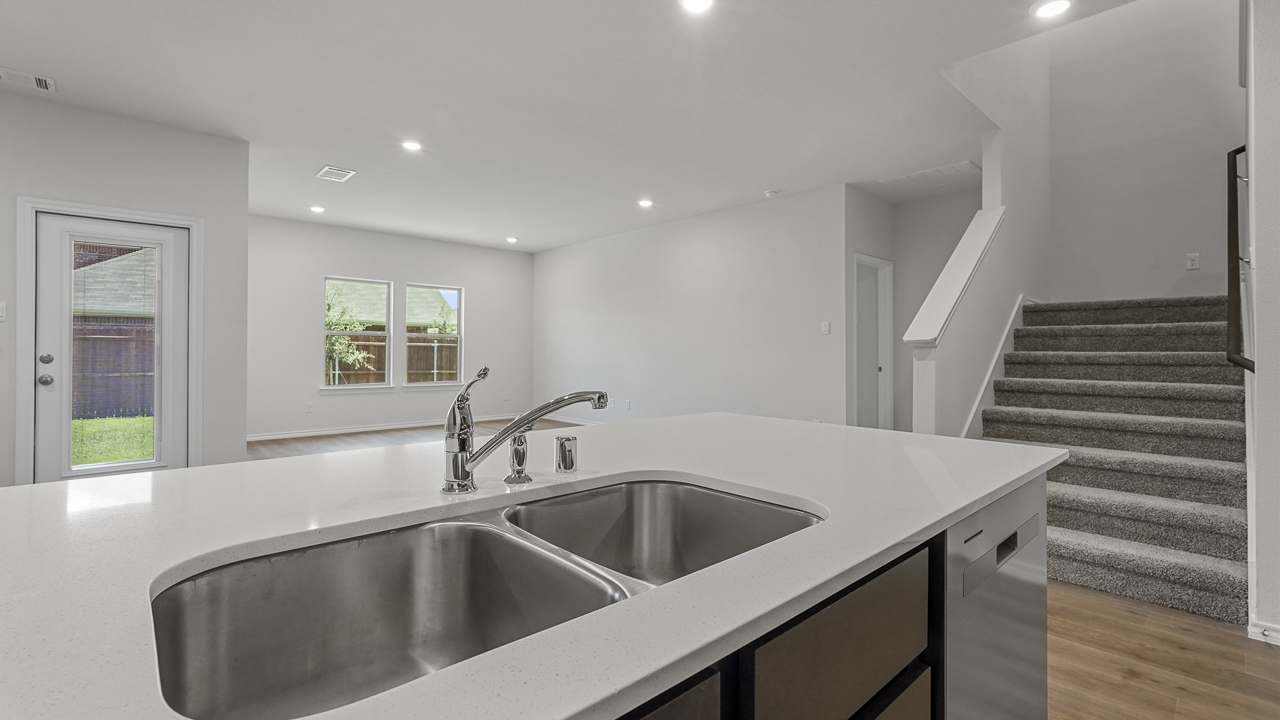 close up of kitchen island with sink next to staircase