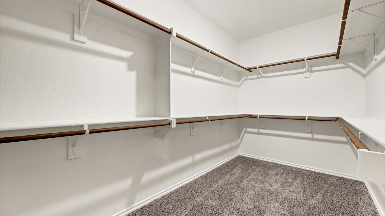 large primary walk in closet with extra hanging rods and storage shelves