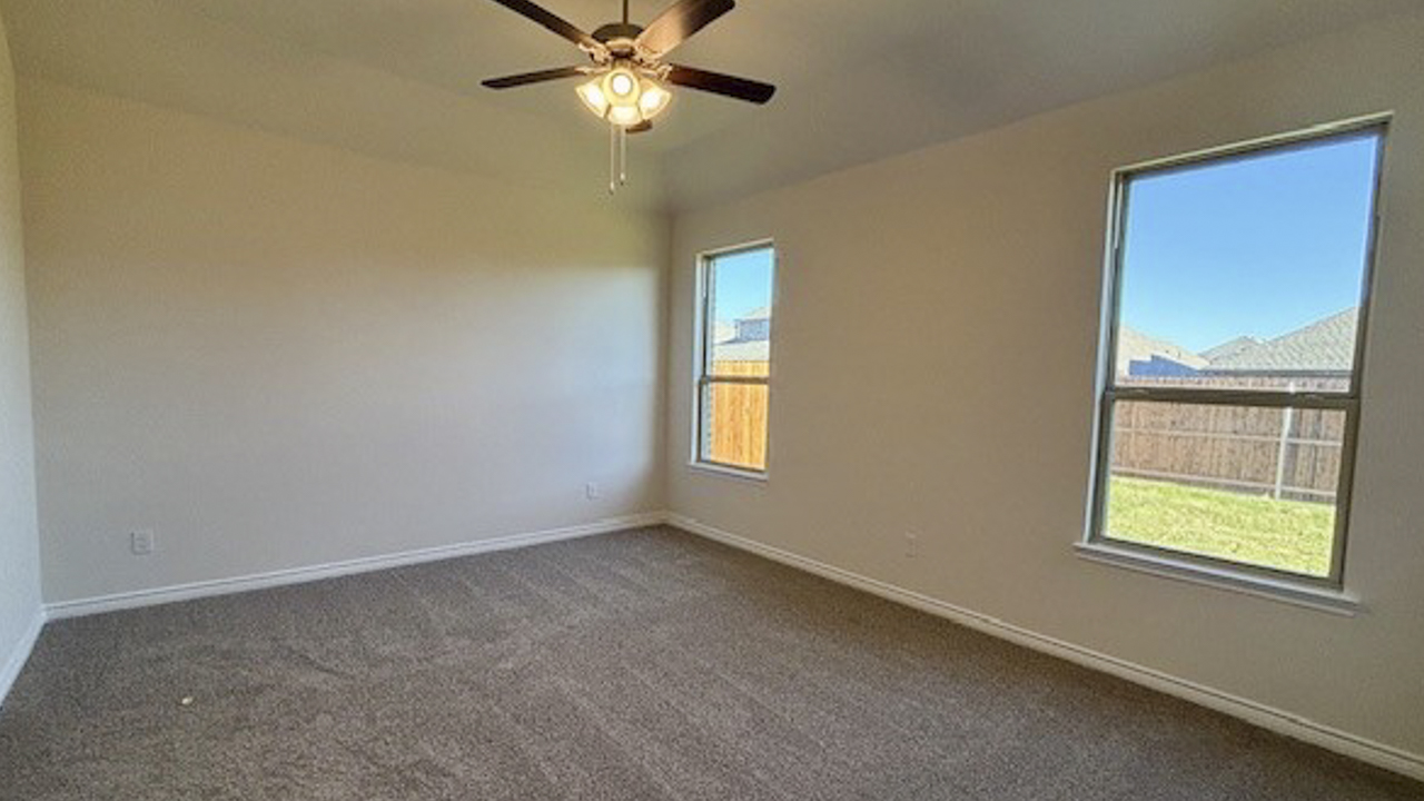 primary bedroom with large windows facing the backyard providing natural light