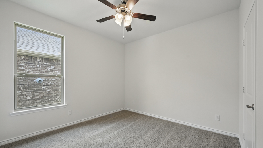 secondary bedroom with carpet and large window providing natural light with white walls