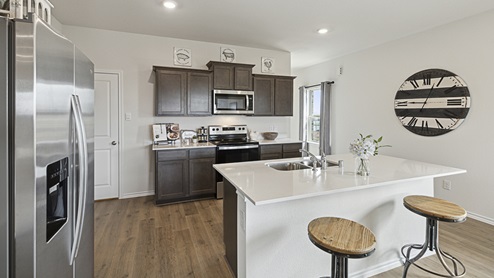 2015 Wildcat Trail model home at Wildcat Ranch in Crandall, TX kitchen area with granite counters and dark cabinets