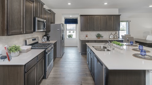 Large kitchen with island surrounded by brown cabinets and hard surface countertops