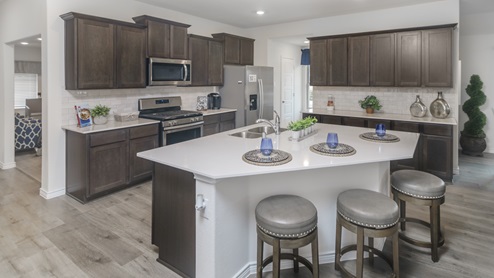 Large kitchen with island surrounded by brown cabinets and hard surface countertops