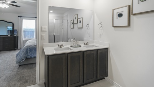Large primary bathroom with brown cabinet vanity and white hard surface countertop