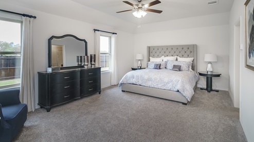 Large primary bedroom with two windows and furnishings