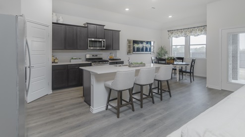 Kitchen with island surrounded by brown cabinets with hard surface countertops and stainless steel appliances
