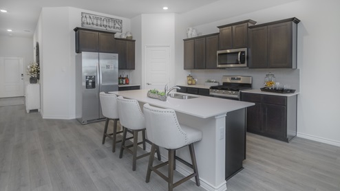 Kitchen with island surrounded by brown cabinets with hard surface countertops and stainless steel appliances