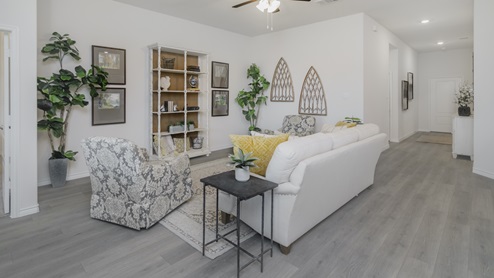 Living area with windows and beautiful furnishings and a view into the elongated entry hallway