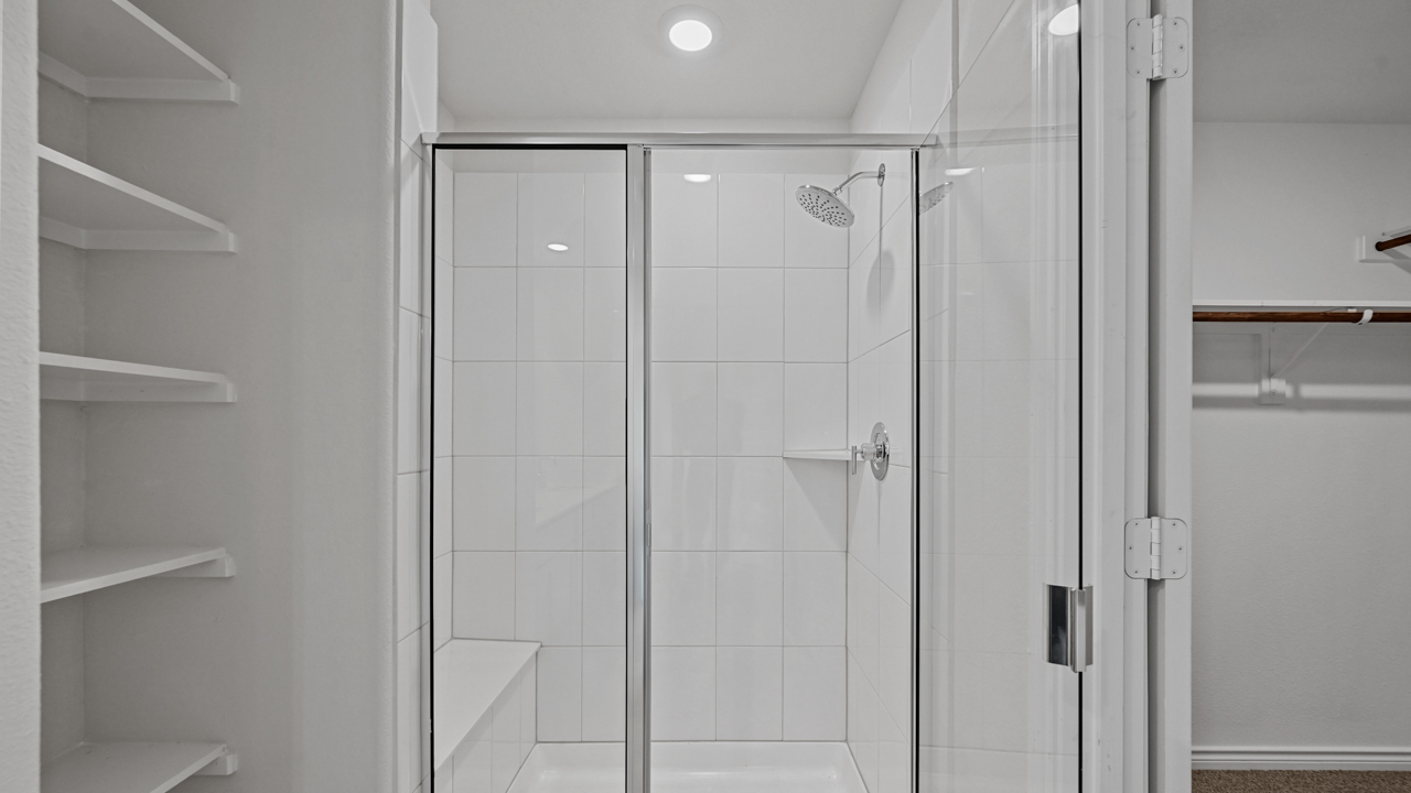 glass shower next to built in shelves