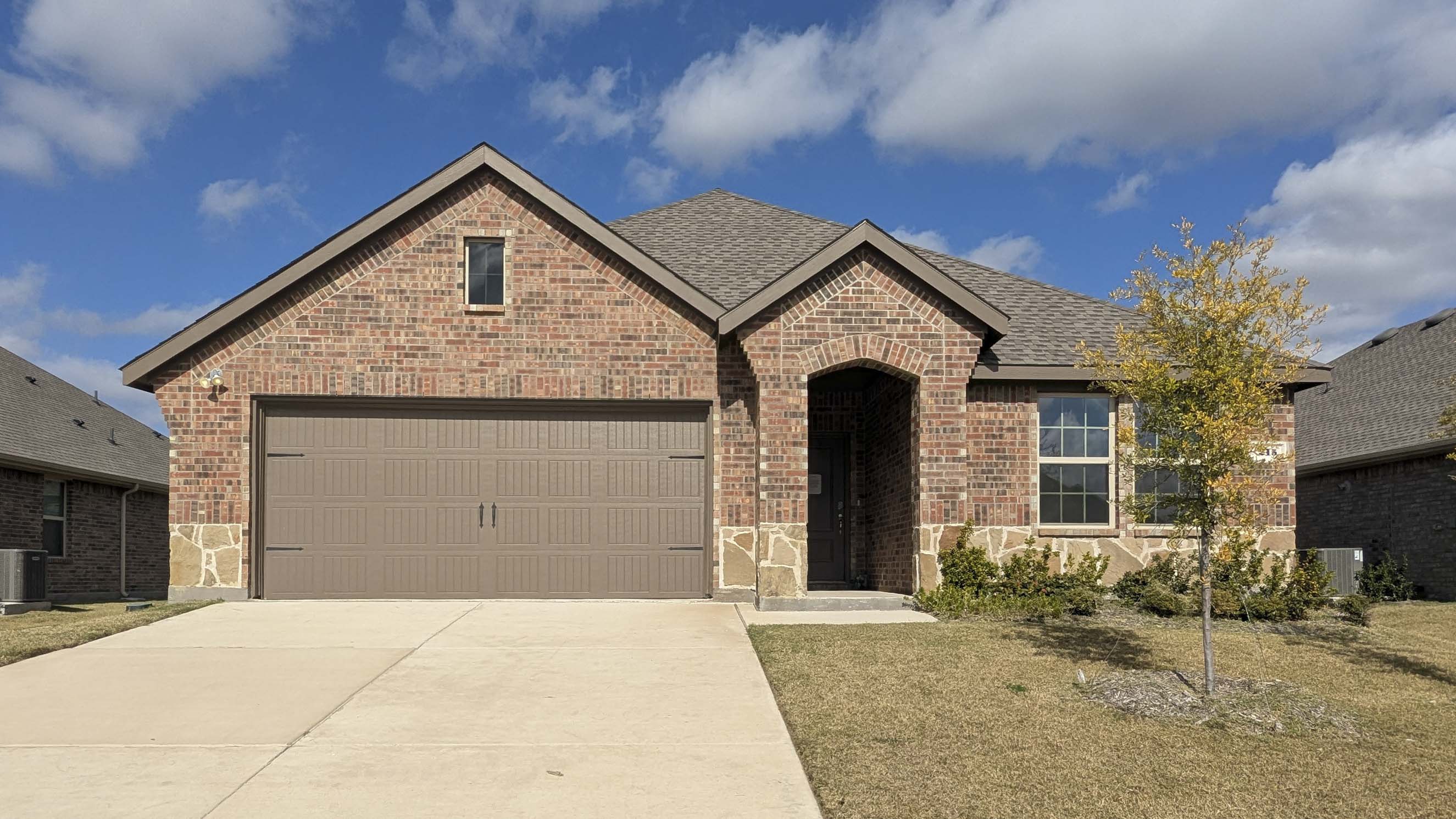exterior of one story home with brick and stone and middle entry to the home