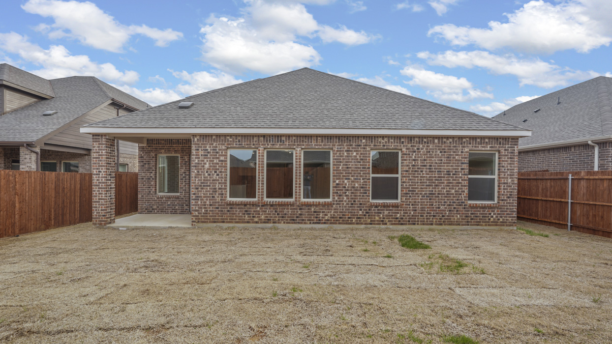 back view of single story home with brick and covered patio