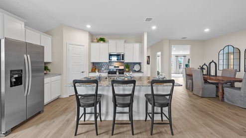 Open-concept kitchen with stainless steel appliances and a large island and white cabinets