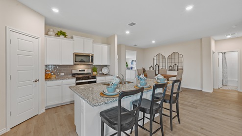 Open-concept kitchen with stainless steel appliances and a large island and white cabinets