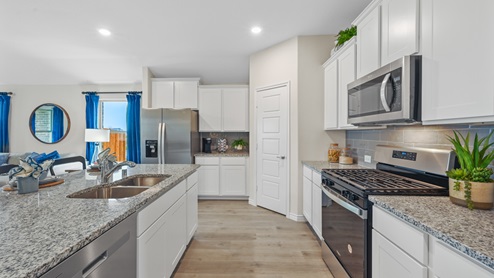 Open-concept kitchen with stainless steel appliances and a large island and white cabinets