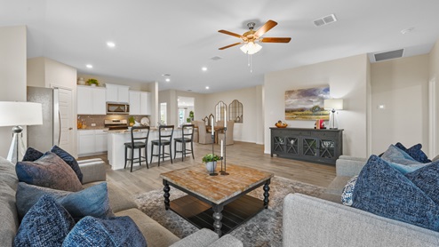 A large open living room with three windows and a ceiling fan