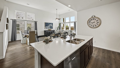 kitchen with large island with white counters and brown cabinets with views into living room
